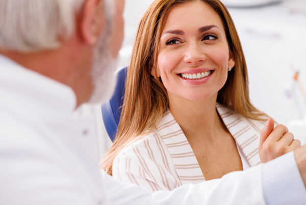 Smiling female dental patient talking to a dentist during consultation at a modern clinic.