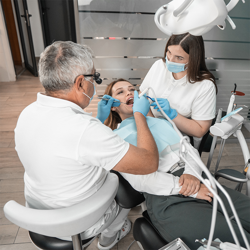Female patient undergoing dental check-up with two professionals