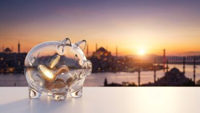 Un cerdito hucha de cristal moderno sobre una superficie blanca y limpia. Al fondo, la vista panorámica y desenfocada de la ciudad de Estambul, Turquía, al amanecer. La imagen simboliza el ahorro en tratamientos de implantes dentales al viajar.