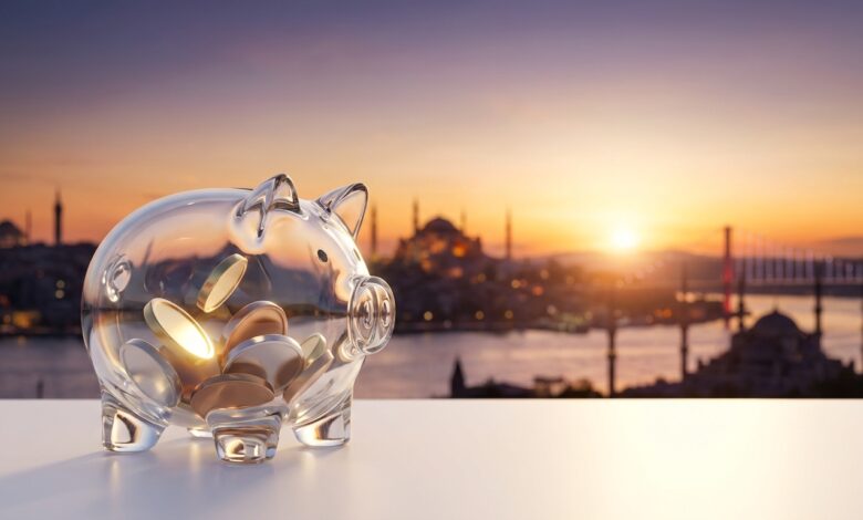 Un cerdito hucha de cristal moderno sobre una superficie blanca y limpia. Al fondo, la vista panorámica y desenfocada de la ciudad de Estambul, Turquía, al amanecer. La imagen simboliza el ahorro en tratamientos de implantes dentales al viajar.