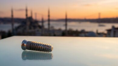 Un implante dental de titanio en primer plano, con el horizonte icónico y desenfocado de Estambul, Turquía, al atardecer como fondo.