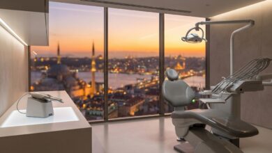 Una sala de clínica dental de última generación, vacía y limpia, con un sillón dental en primer plano y una vista panorámica y desenfocada de la silueta de Estambul a través de una gran ventana al amanecer.