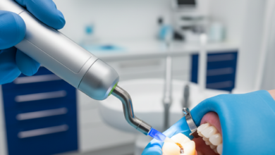 Imagen fotorrealista de un primer plano de un diente siendo restaurado con composite, aislado con un dique de goma. Se ve la mano enguantada de un dentista aplicando luz de fotopolimerización sobre el diente en una clínica dental moderna y estéril.