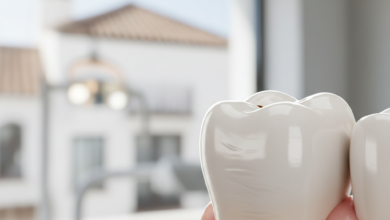 Primer plano fotorealista de un diente con una corona dental de aspecto natural, perfectamente integrada. El fondo está suavemente desenfocado, mostrando un interior de clínica dental moderno con un sutil detalle arquitectónico español en la distancia.
