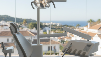 Interior de una clínica dental moderna y luminosa en España, mostrando una silla dental ergonómica y equipos de alta tecnología. A través de una gran ventana, se vislumbra un paisaje urbano o costero español difuminado. La imagen transmite calma y tecnología, sin texto.