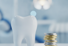 Primer plano de un diente molar blanco y saludable junto a una pila de monedas de oro y plata genéricas. El fondo está difuminado, mostrando el interior de una clínica dental moderna con iluminación suave.