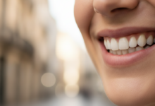 Primer plano fotorrealista de la sonrisa de un adulto con dientes sanos y limpios, sobre un fondo urbano español difuminado y bañado por el sol.